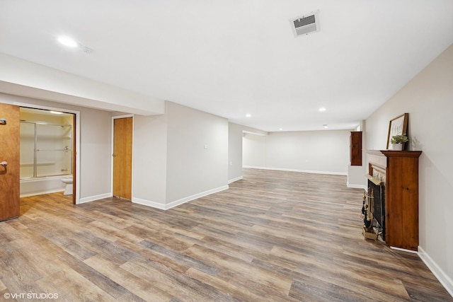 finished basement featuring recessed lighting, wood finished floors, baseboards, and a fireplace