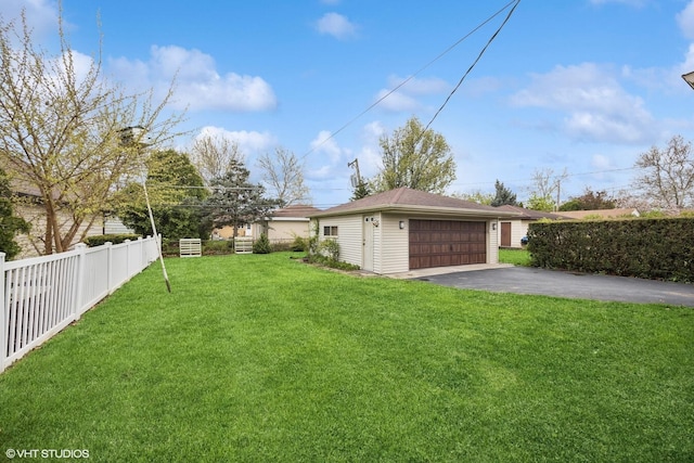 view of yard featuring asphalt driveway and a garage