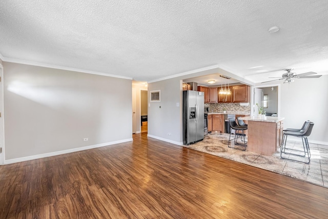 living room with light wood-style floors, a textured ceiling, baseboards, ceiling fan, and ornamental molding