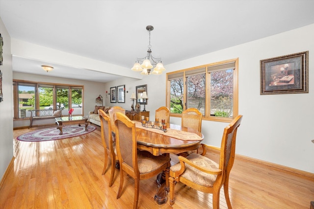 dining space featuring a chandelier, light wood-style flooring, and baseboards