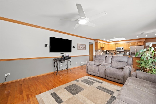 living area featuring ornamental molding, light wood-style floors, ceiling fan, baseboards, and recessed lighting