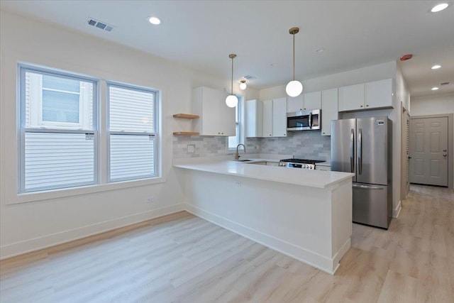 1808 N Karlov Ave, Chicago, IL 60639 - kitchen featuring stainless steel appliances, a sink, light countertops, light wood-type flooring, and a peninsula