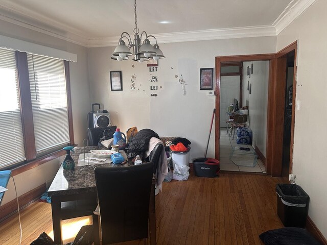 dining room with a chandelier, wood finished floors, and crown molding