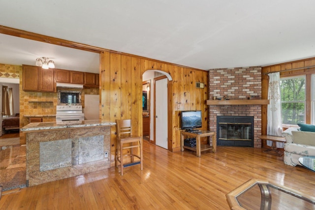 26211 W Spring Grove Rd, Antioch, IL 60002 - living room with wood walls, arched walkways, light wood-style flooring, and a brick fireplace