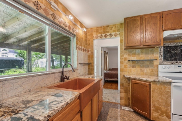 26211 W Spring Grove Rd, Antioch, IL 60002 - kitchen featuring white electric stove, under cabinet range hood, backsplash, light stone counters, and tile walls