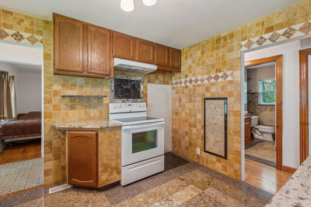 26211 W Spring Grove Rd, Antioch, IL 60002 - kitchen featuring white range with electric stovetop, tile walls, under cabinet range hood, light countertops, and brown cabinets