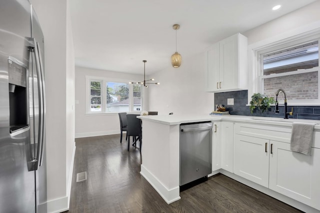 kitchen with appliances with stainless steel finishes, a sink, dark wood-style floors, tasteful backsplash, and white cabinets