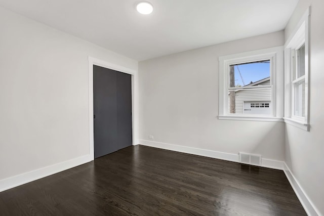 unfurnished room featuring dark wood-style flooring and baseboards