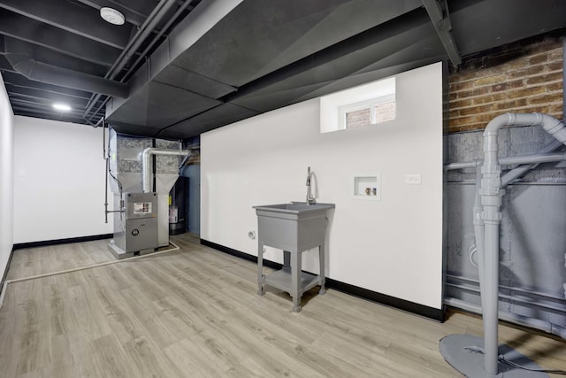 below grade area with wood finished floors, heating unit, and baseboards