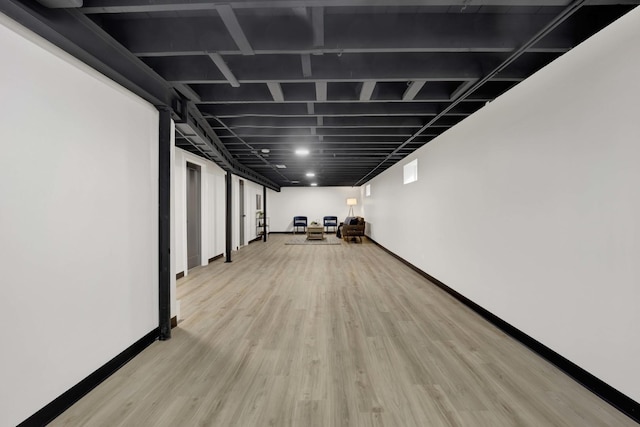 finished below grade area with light wood-style floors and baseboards