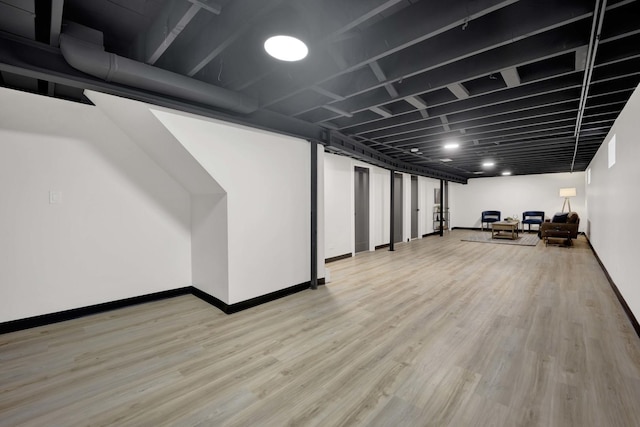 finished below grade area featuring baseboards and light wood-style flooring