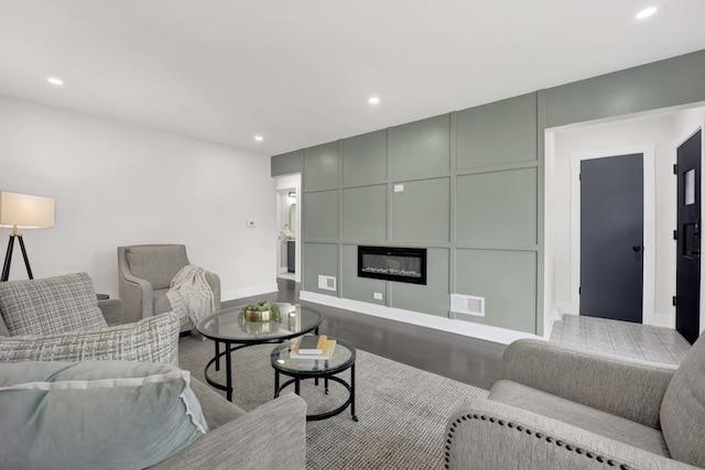 living area featuring wood finished floors, recessed lighting, baseboards, a fireplace, and a decorative wall
