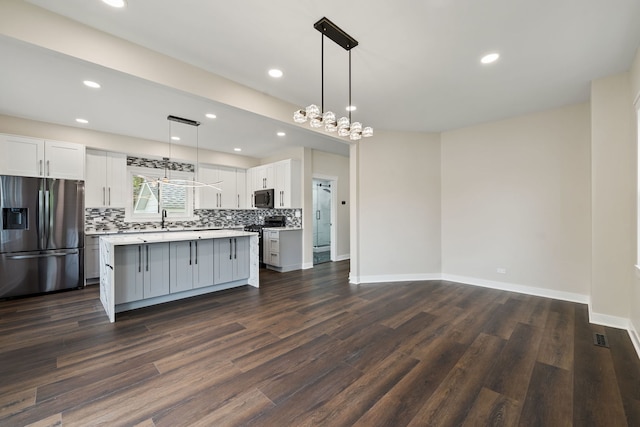 kitchen featuring stainless steel refrigerator with ice dispenser, range with gas cooktop, white cabinetry, tasteful backsplash, and dark wood-type flooring
