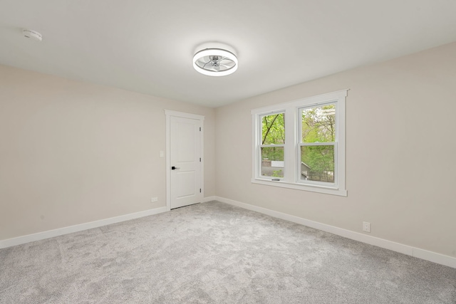 carpeted spare room featuring a smoke detector and baseboards