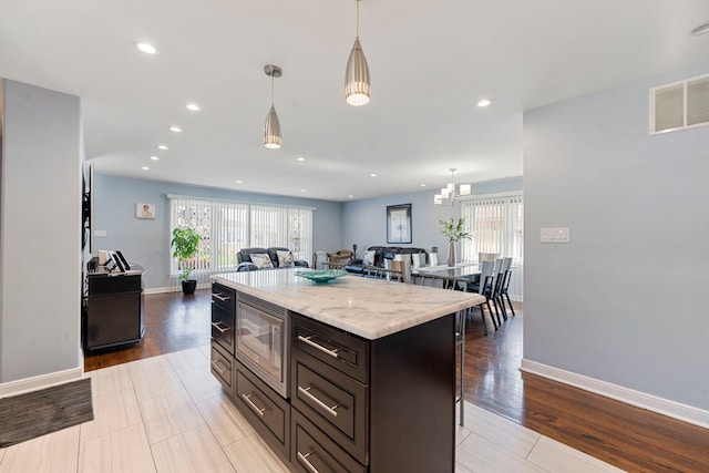 8557 W Winona St, Chicago, IL 60656 - kitchen with stainless steel microwave, plenty of natural light, hanging light fixtures, and recessed lighting