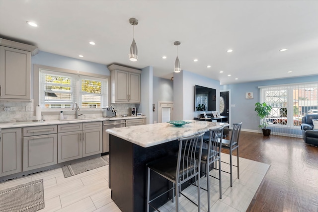 8557 W Winona St, Chicago, IL 60656 - kitchen with gray cabinetry, dishwasher, a sink, a kitchen bar, and decorative backsplash