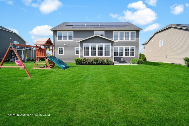 rear view of house with a playground, roof mounted solar panels, a yard, and a patio area