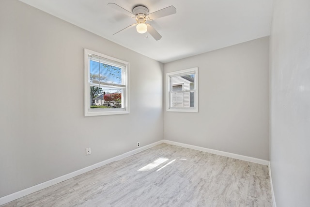 spare room with wood finished floors, a ceiling fan, and baseboards