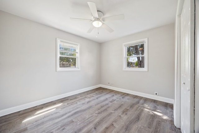 empty room featuring wood finished floors, baseboards, and ceiling fan