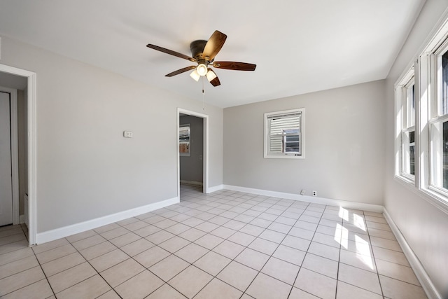 spare room featuring a ceiling fan, baseboards, and light tile patterned floors