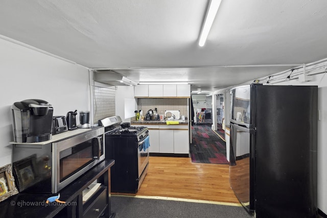 kitchen featuring appliances with stainless steel finishes, extractor fan, white cabinetry, and light wood-style flooring
