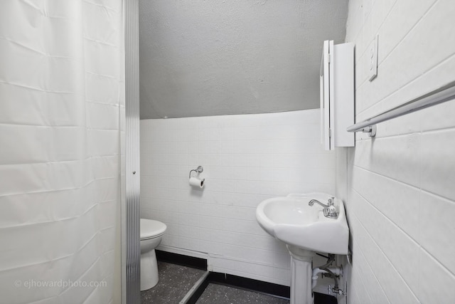 bathroom with toilet, tile walls, and a shower with shower curtain