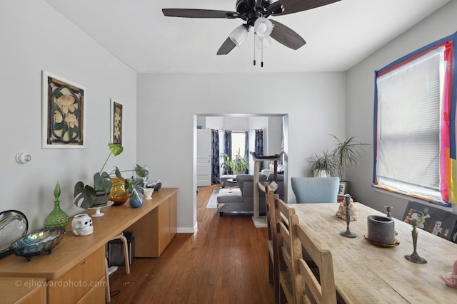 dining room with dark wood-type flooring, a ceiling fan, and baseboards