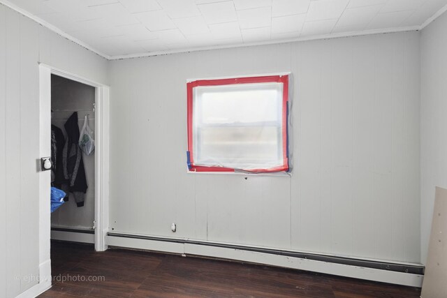 unfurnished bedroom with baseboard heating, wood finished floors, and crown molding
