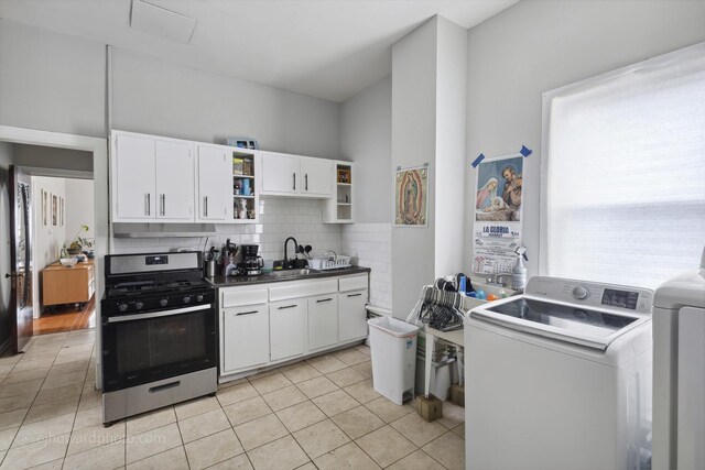 kitchen with stainless steel range with gas stovetop, open shelves, light tile patterned flooring, tasteful backsplash, and white cabinets