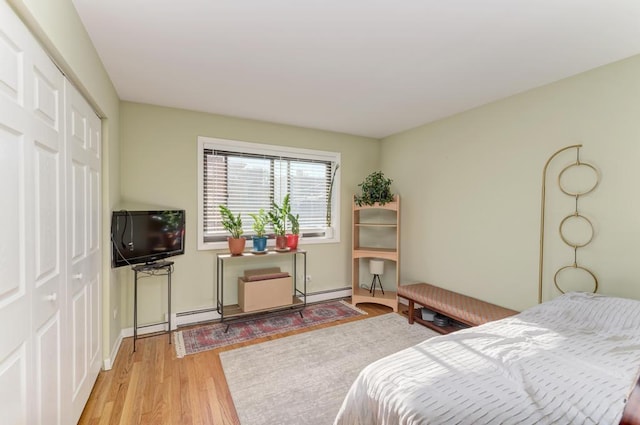 bedroom with wood finished floors, a closet, and baseboard heating