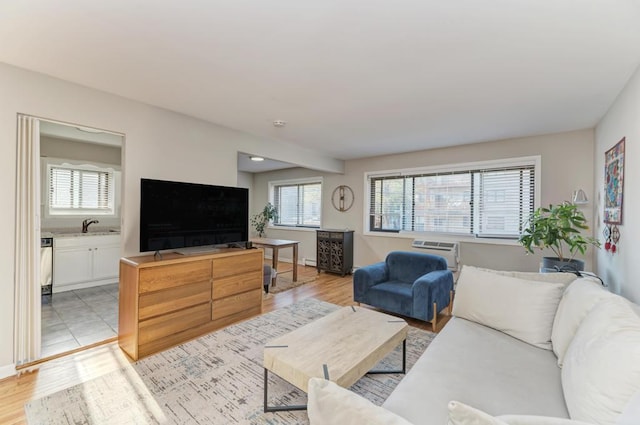 living area with healthy amount of natural light, light wood-type flooring, and a wall unit AC