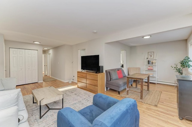 living room with baseboard heating, light wood-style flooring, and baseboards