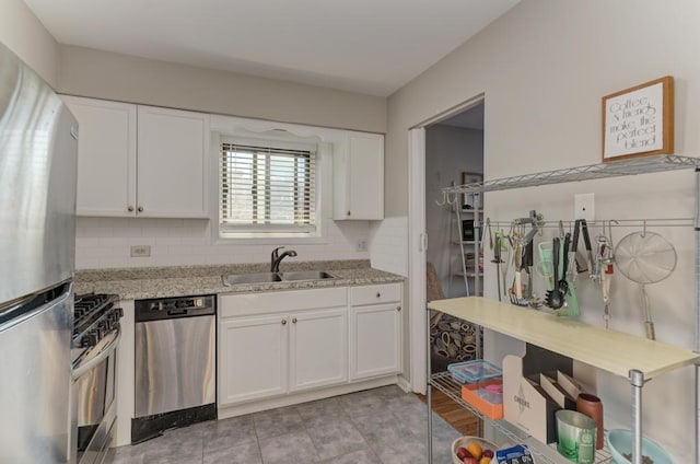 kitchen with stainless steel appliances, a sink, white cabinets, tasteful backsplash, and light stone counters