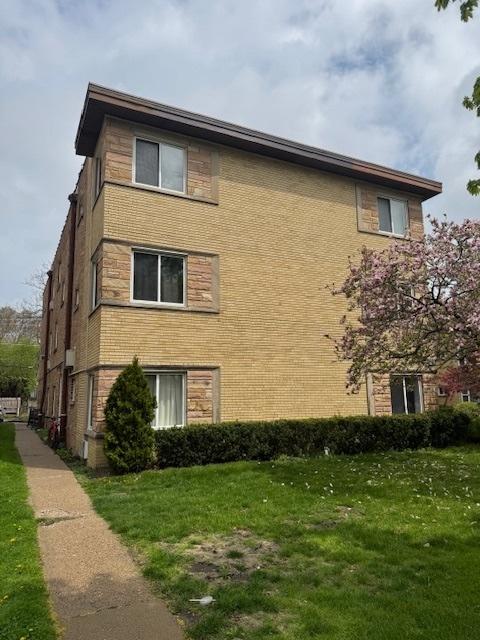 view of side of property featuring a yard and brick siding