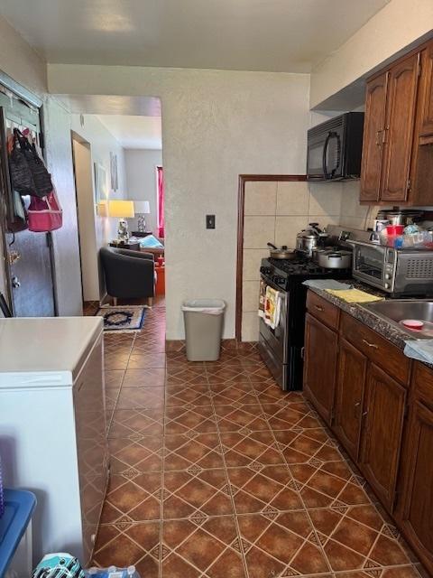 kitchen with black microwave, range with gas cooktop, refrigerator, and a sink