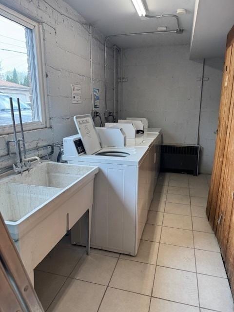 shared laundry featuring light tile patterned floors, washer and dryer, and concrete block wall