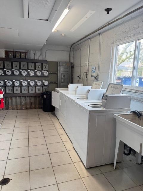 laundry room featuring a sink, washer and clothes dryer, and light tile patterned floors