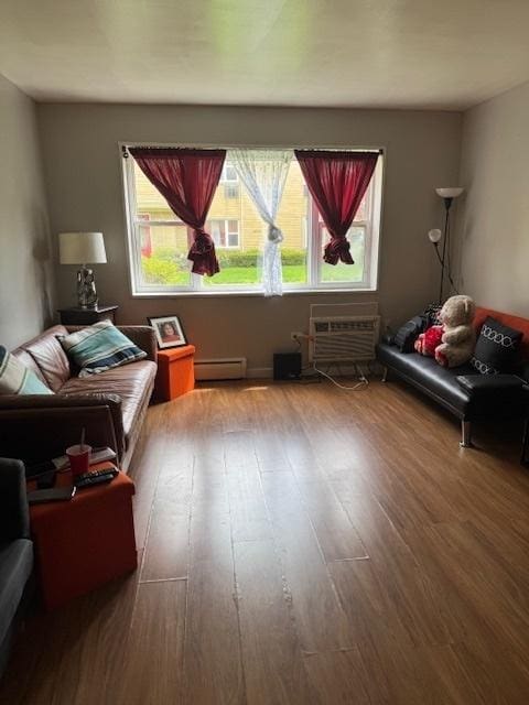 bedroom featuring a baseboard heating unit, wood finished floors, and multiple windows