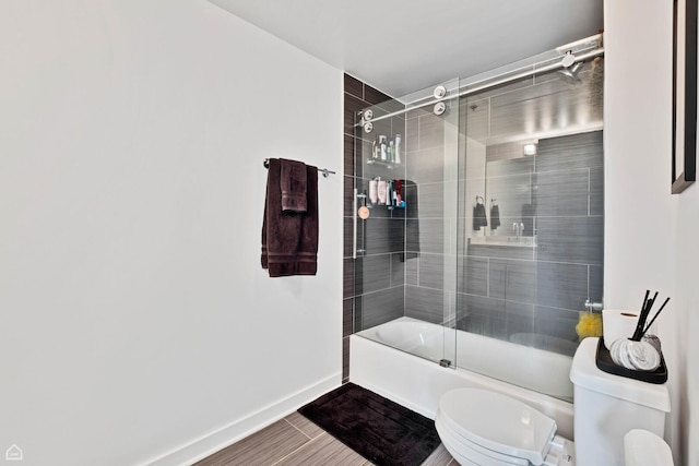 full bath featuring toilet, shower / bath combination with glass door, and baseboards