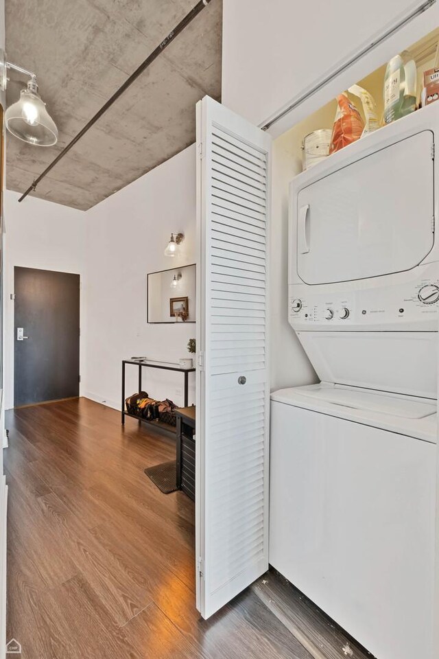 washroom with stacked washer and clothes dryer and wood finished floors