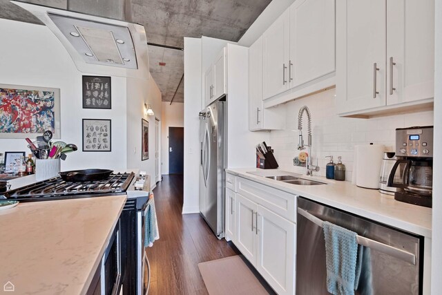 kitchen with stainless steel appliances, a sink, dark wood finished floors, white cabinets, and tasteful backsplash