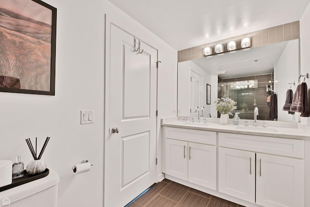 full bathroom featuring a stall shower, toilet, and double vanity