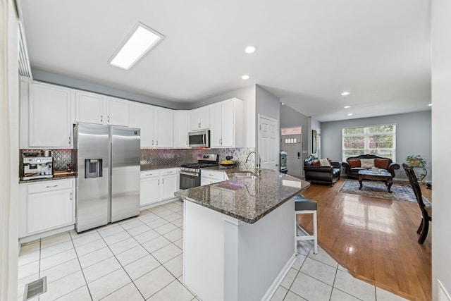 1892 Keystone Pl, Schaumburg, IL 60193 - kitchen featuring stainless steel appliances, a sink, a peninsula, dark stone countertops, and white cabinets