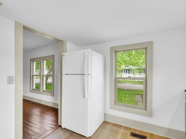 413 E Lincoln St, Monticello, IL 61856 - unfurnished bedroom featuring freestanding refrigerator, multiple windows, and wood finished floors