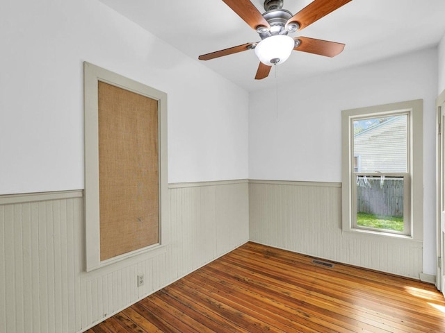 413 E Lincoln St, Monticello, IL 61856 - unfurnished room featuring a wainscoted wall, wood-type flooring, a ceiling fan, and wooden walls
