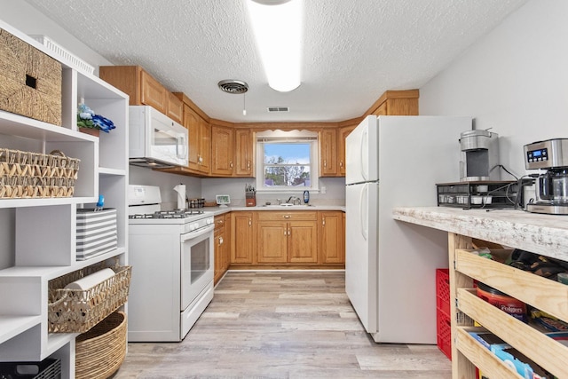 kitchen featuring white appliances, light wood-style floors, a sink, light countertops, and a textured ceiling