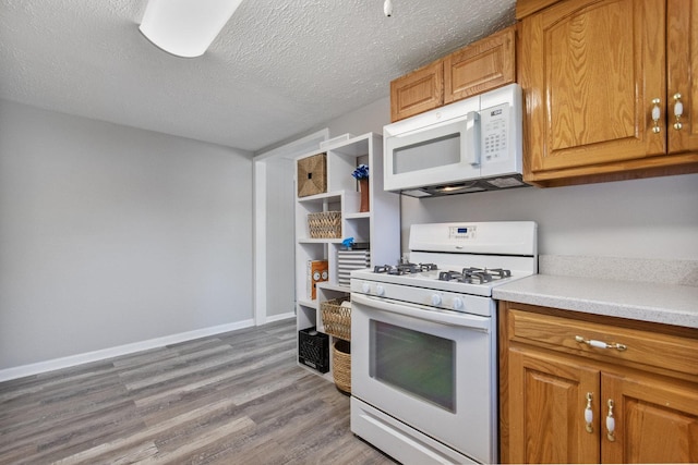 kitchen with white appliances, light wood-style flooring, light countertops, brown cabinetry, and a textured ceiling