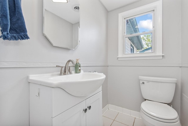 half bathroom with vanity, toilet, baseboards, and tile patterned flooring