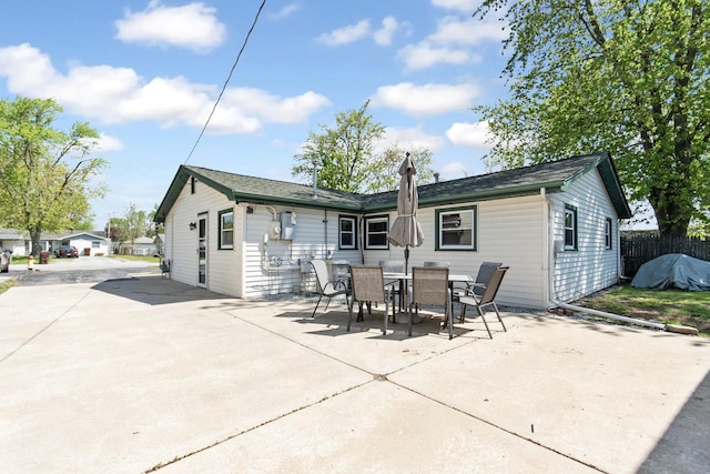 rear view of property featuring a patio area, fence, and outdoor dining area