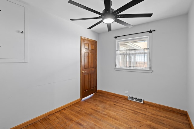 spare room featuring baseboards, light wood finished floors, and a ceiling fan